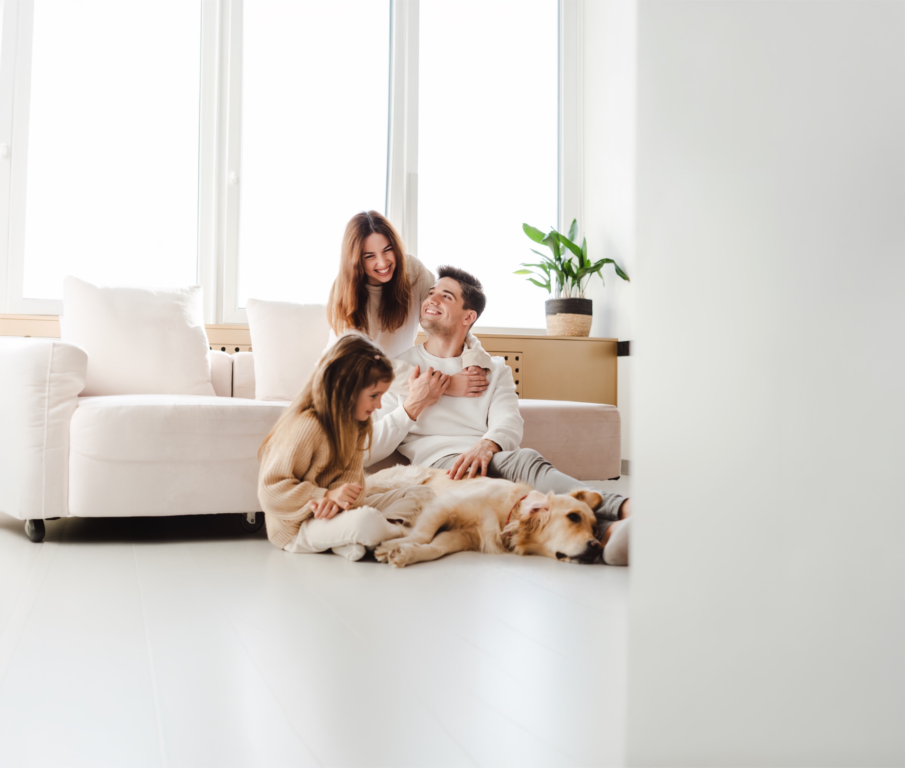 Casal, filha e cachorro relaxando no chão de uma sala branca, clara e protegida